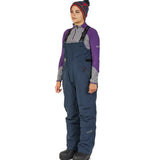 Woman in navy blue ice fishing bibs with purple thermal layer, ideal for cold weather outdoor gear