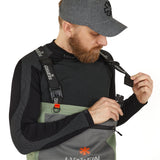 Man adjusting Norfin fishing bib with adjustable straps and orange accents for outdoor gear comfort